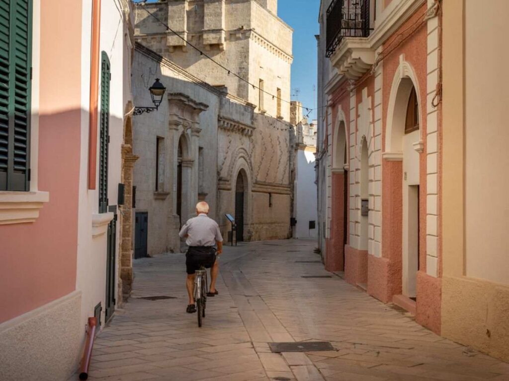 Uomo in bicicletta in una via di Presicce